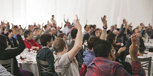 people in a room raising their hands to vote